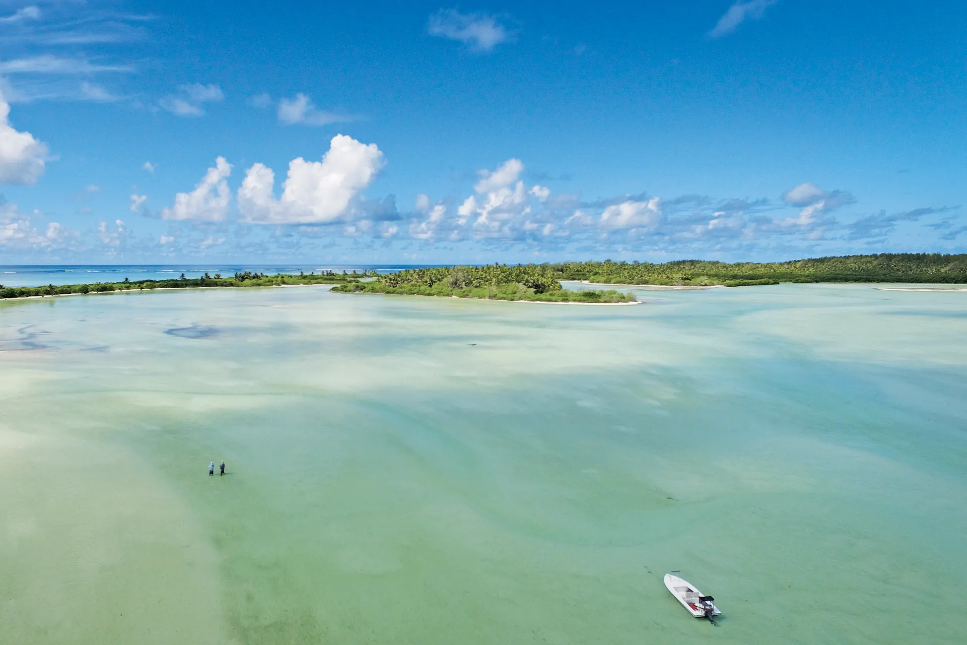 Wide shallow flat with anglers and a skiff at St Francois Atoll