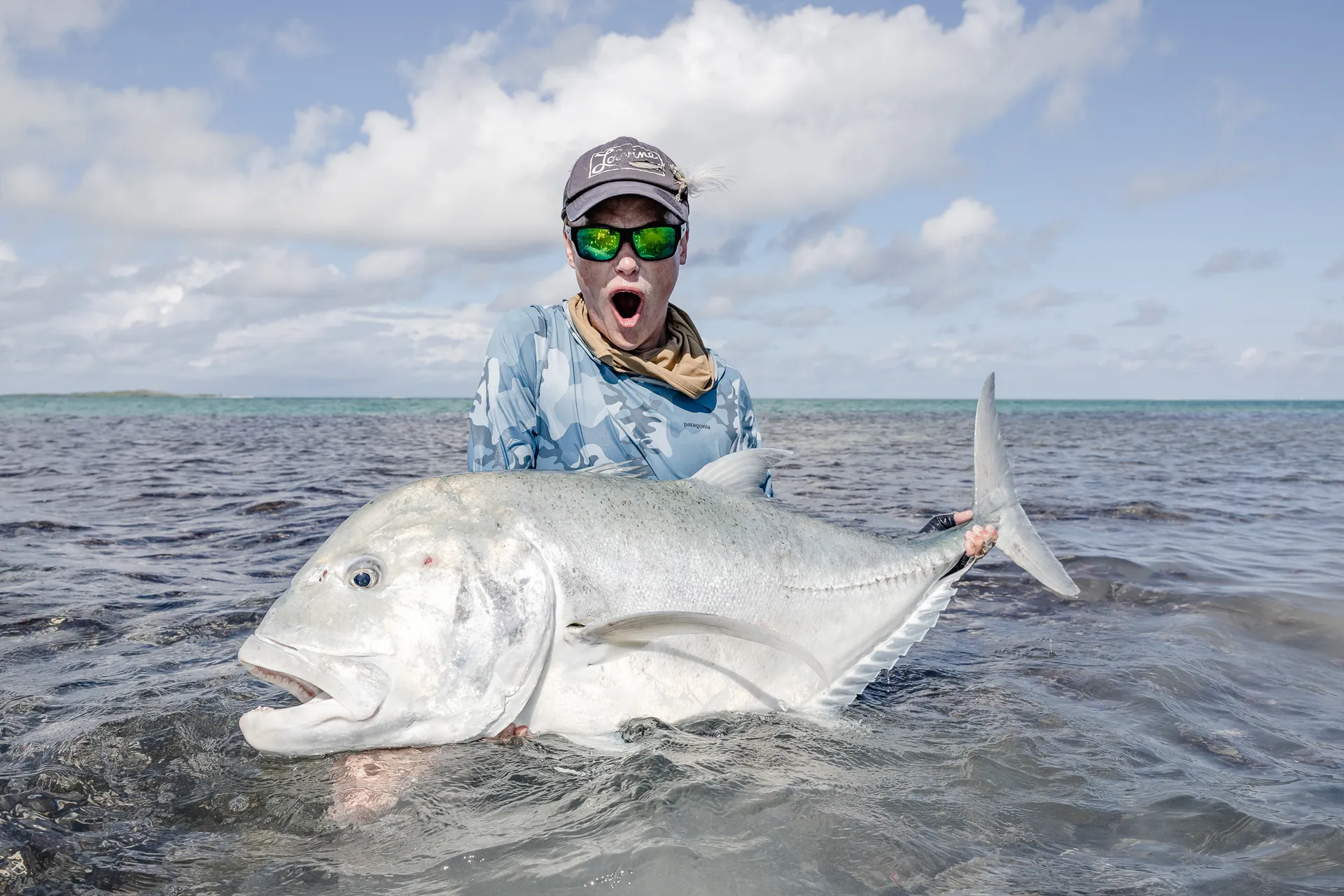 Angler beaming while holding a giant trevally caught at St Francois Atoll